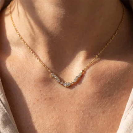 Gold chain necklace with a row of diamond-studded settings resting on the collarbone.