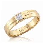 Gold band with a square-cut diamond set in a bezel on the top, showing a polished finish and inner engraving.