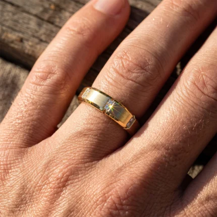 Close-up of a gold ring with small diamonds worn on the ring finger, sunlight creating a sparkle.