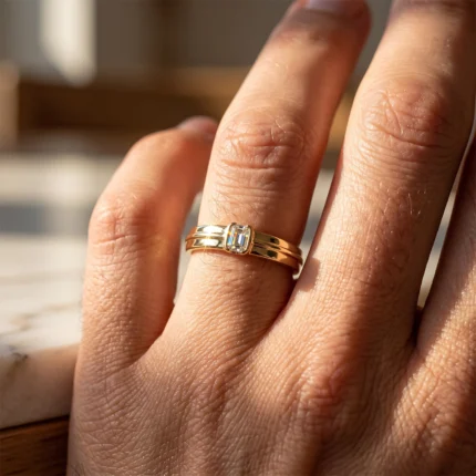 Close-up of a gold ring with a square blue gemstone on a finger.