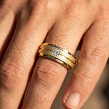 Close-up of a gold multi-band ring with a single diamond on a finger.