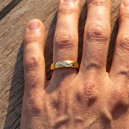 Close-up of a hand showing a gold two-tone ring with a small diamond on the ring finger, resting on a wooden surface.