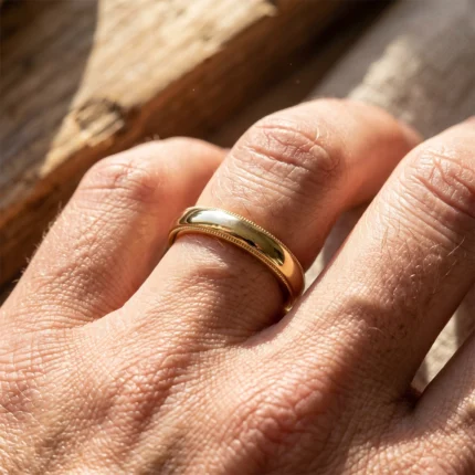Close-up of a gold wedding band on a finger in warm light.