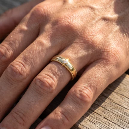 Close-up of a hand wearing two gold rings, one with a square diamond catching the sunlight on the finger.