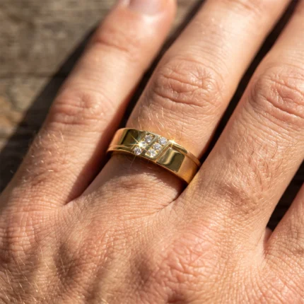 Close-up of a gold ring with three small diamonds on a finger, catching the sunlight.