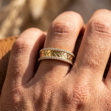 Close-up of a finger wearing two gold rings with diamond pavé edges on the bands.