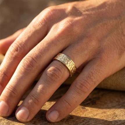 Close-up of a hand wearing a hammered two-tone gold ring on the ring finger.