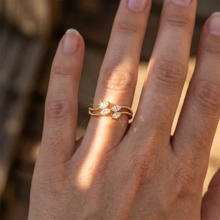Gold beaded ring with two marquise-cut diamonds on a finger, sunlight creating a sparkle.