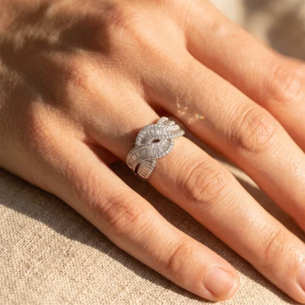 Close-up of a diamond-studded swirling ring on a finger, showcasing intricate metalwork and sparkle.