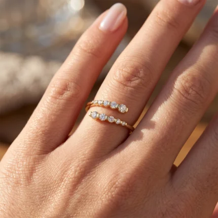 Two rose-gold stackable rings with alternating diamonds on a finger, close-up in sunlight.