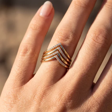 Gold multi-band ring with chevron-shaped, diamond-studded rows on a finger.