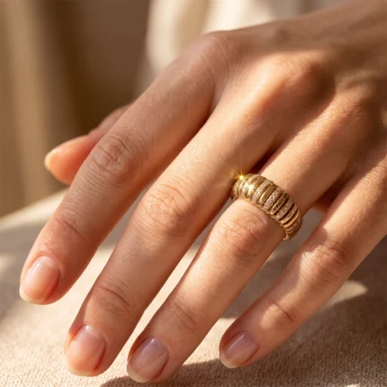 Close-up of a hand wearing a gold multi-band ring with diamonds sparkling in sunlight on the ring finger.