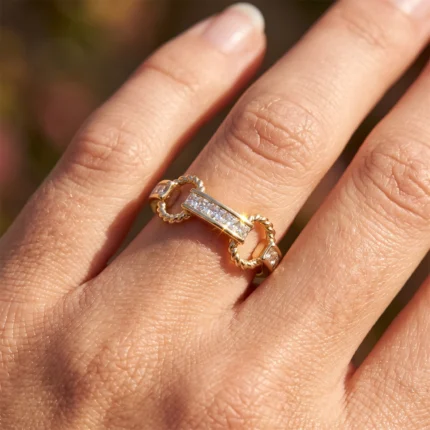 Close-up of a gold ring with a rectangular diamond centerpiece on a finger