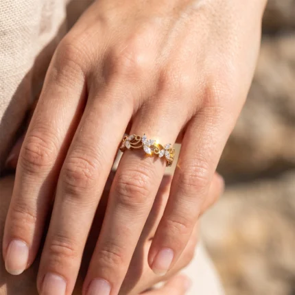 Gold ring with leaf-shaped diamond accents on a woman's left ring finger (close-up).