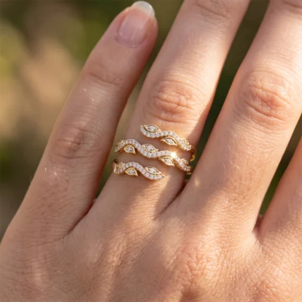 Gold ring stack with leaf-shaped, diamond-encrusted bands on a finger.