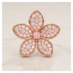 Rose-gold flower-shaped brooch encrusted with pink stones, on a pale background (product image).