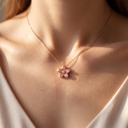 Rose-gold necklace with a four-petaled crystal flower pendant resting on a woman's décolletage.