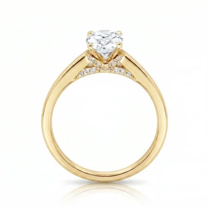 Gold engagement ring with a round diamond solitaire and pavé diamonds along the shoulders, set in a yellow gold band.