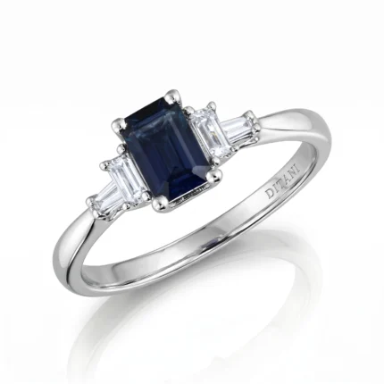 Palladium/silver ring with a deep blue rectangular sapphire center, flanked by baguette diamonds on a sleek metal band.