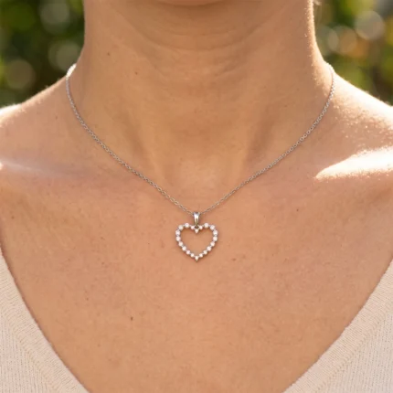 Silver heart-shaped diamond pendant necklace resting on a person's bare neckline