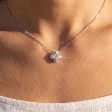 Silver chain necklace with a diamond-encrusted four-leaf clover pendant resting on the chest.