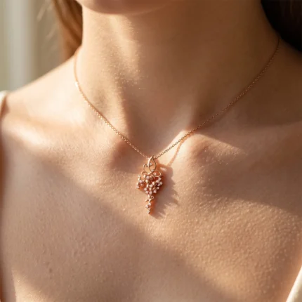 Close-up of a woman wearing a rose-gold necklace with a floral crystal pendant resting on the collarbone.
