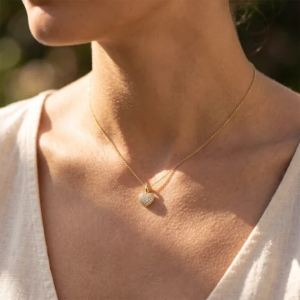 Close-up of a gold heart pendant necklace on a woman's neck and collarbone.
