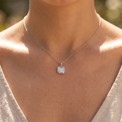 Silver chain necklace with an octagonal, diamond-encrusted pendant resting on the collarbone of a person outdoors.