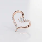 Rose gold heart-shaped ring with a central diamond and pavé diamonds along the curved band in a heart form.