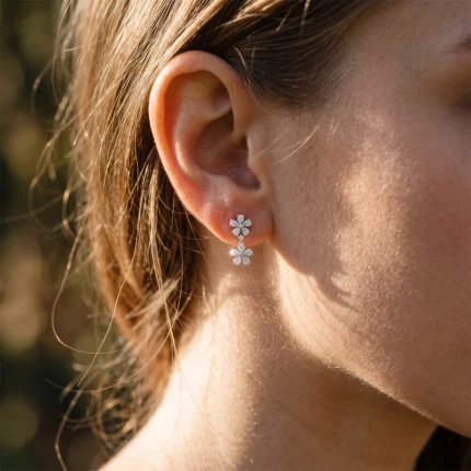 Close-up of a woman's ear wearing a double-flower diamond earring with two linked blossoms the earlobe.