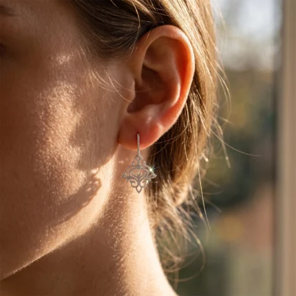 Close-up of a woman's ear with a dangling, ornate silver earring catching sunlight.