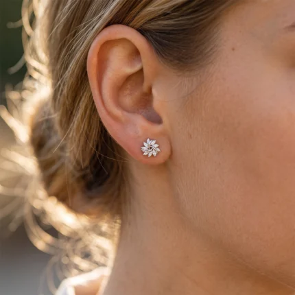 Close-up of a woman's ear wearing a silver flower-shaped diamond stud earring on the earlobe.