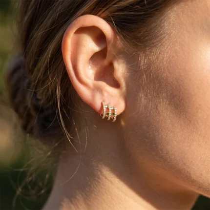 Close-up of a woman's ear with a small gold multi-bar diamond earring on the earlobe