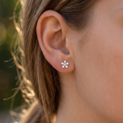Close-up of a ear with a small flower-shaped diamond stud earring in the earlobe