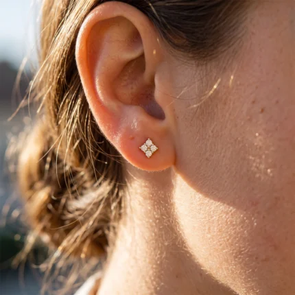 Close-up of a woman's left ear with a diamond four-petal stud earring (floral shape).