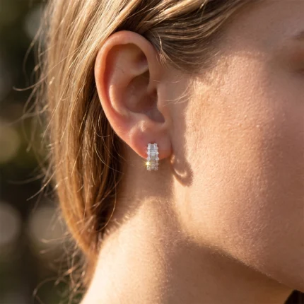 Close-up of a woman's ear wearing a two-row diamond hoop earring that catches the light.