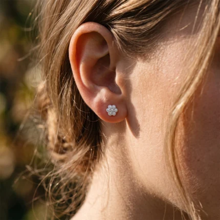 Close-up of a woman's earlobe with a flower-shaped diamond stud earring.