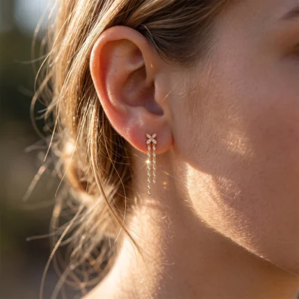 Close-up of an ear wearing a delicate flower-shaped diamond stud with a long, diamond-studded drop chain earring.