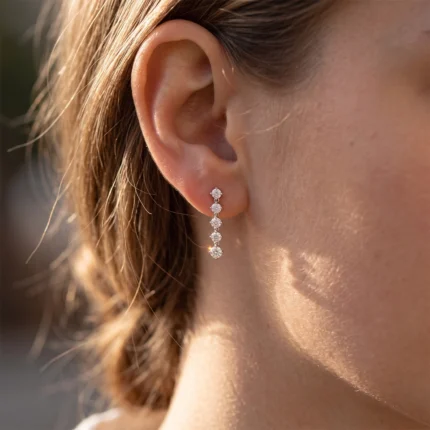 Close-up of a woman's ear wearing a diamond drop earring with five stones in a vertical line.