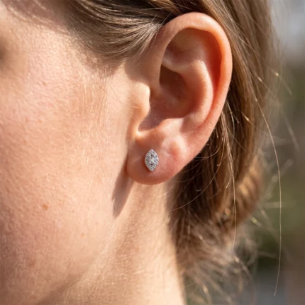 Close-up of a small diamond halo earring on the earlobe with a central rectangular diamond.
