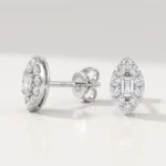White-gold diamond stud earrings with an emerald-cut center stone, surrounded by a halo of round diamonds; one earring shown from the front, the other from the side with post and butterfly backing.