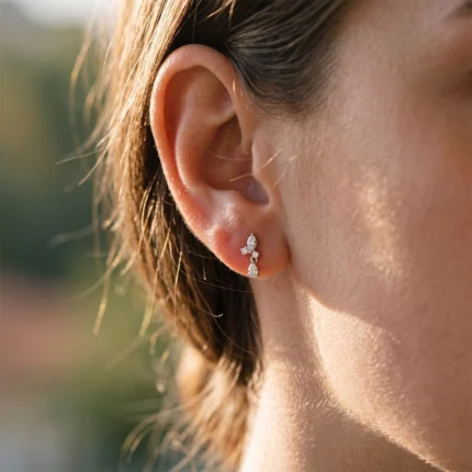 Close-up of a woman's ear with a delicate diamond drop earring shimmering in sunlight