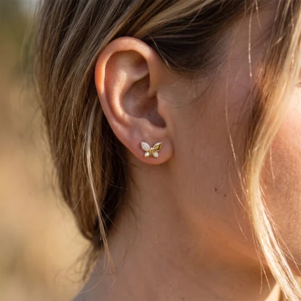 Gold butterfly-shaped stud earring with diamond accents on the left earlobe.