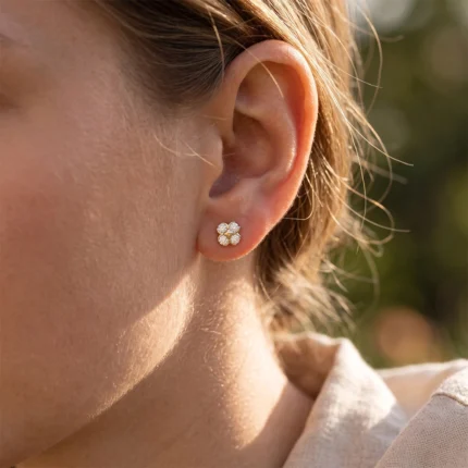 Close-up of a woman's ear wearing a four-diamond flower-shaped stud earring.