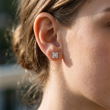 Close-up of a woman's ear with a square halo diamond stud earring on the earlobe.