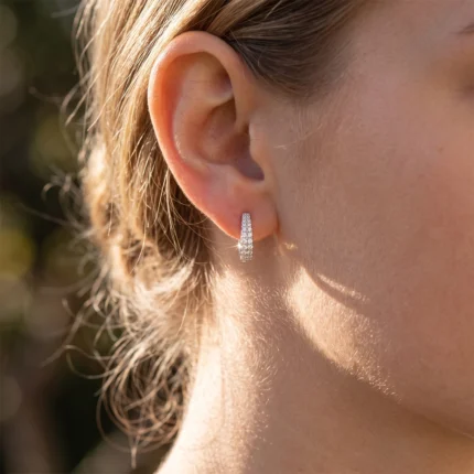 Close-up of a woman's ear with a small diamond-studded hoop earring