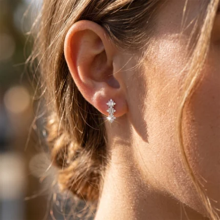 Close-up of a pierced ear with a vertical diamond-embellished drop earring.