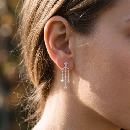 Close-up of a woman's ear wearing a long diamond chandelier earring with multiple drop stones