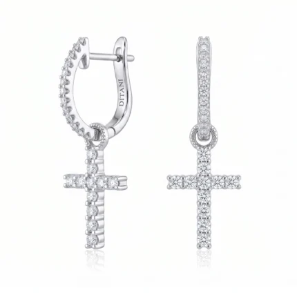 Diamond-studded cross pendant hanging from a silver hoop earring, with pavé diamonds along the hoop and cross edge.