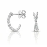 Diamond-studded silver earrings: a pavé hoop and a tall curved drop with diamonds, shown from the side in bright light.